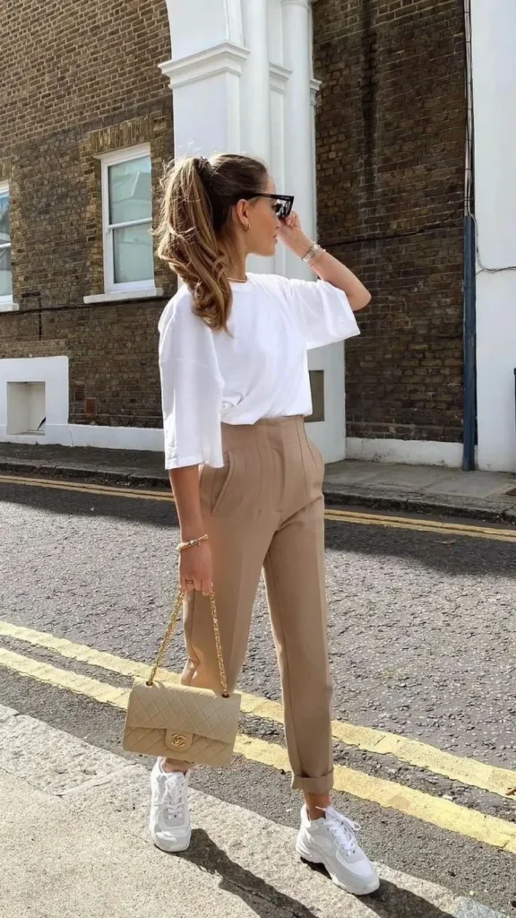  A woman wearing white shirt and casual pants strolls down the street, enjoying her day in a casual outfit.

